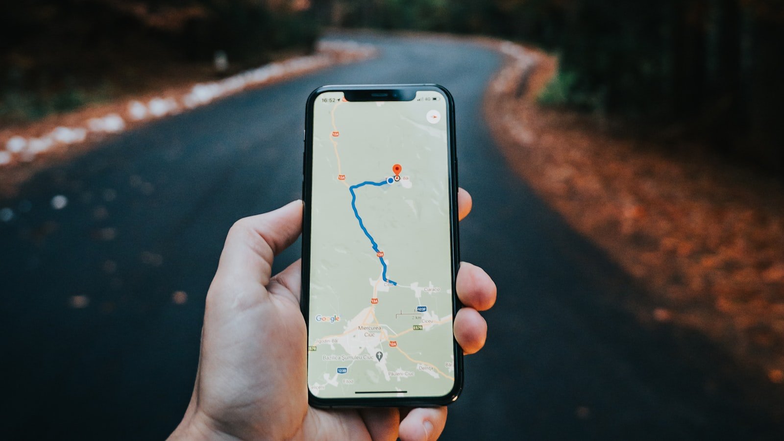 A hand holding a smartphone displaying a navigation map, representing the Google Business Profile signals that move local Map Pack rankings