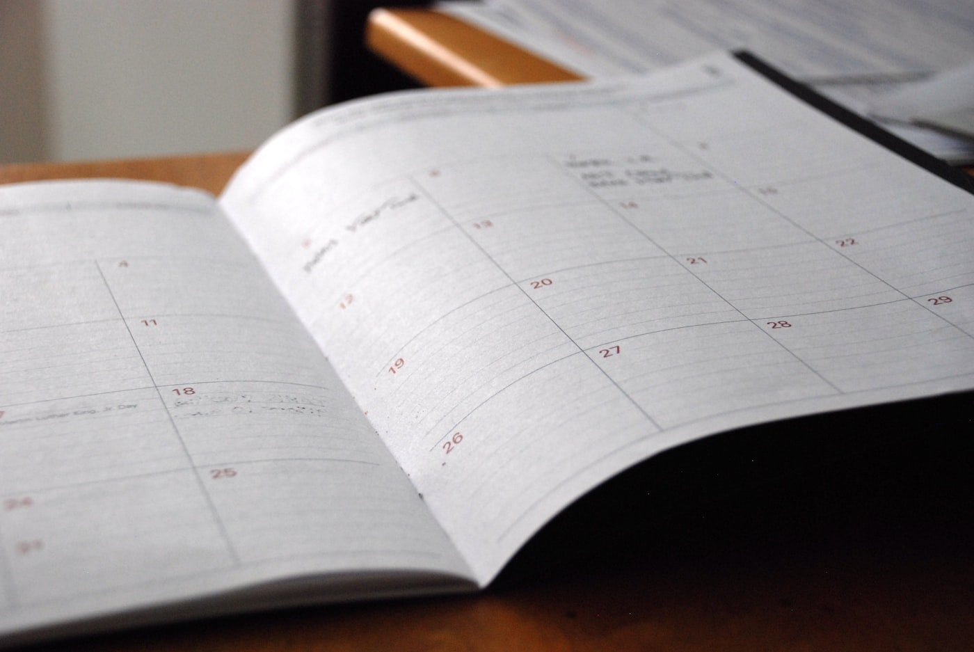 An open monthly planner on a wooden desk, used for mapping out appointment and booking rules before setup