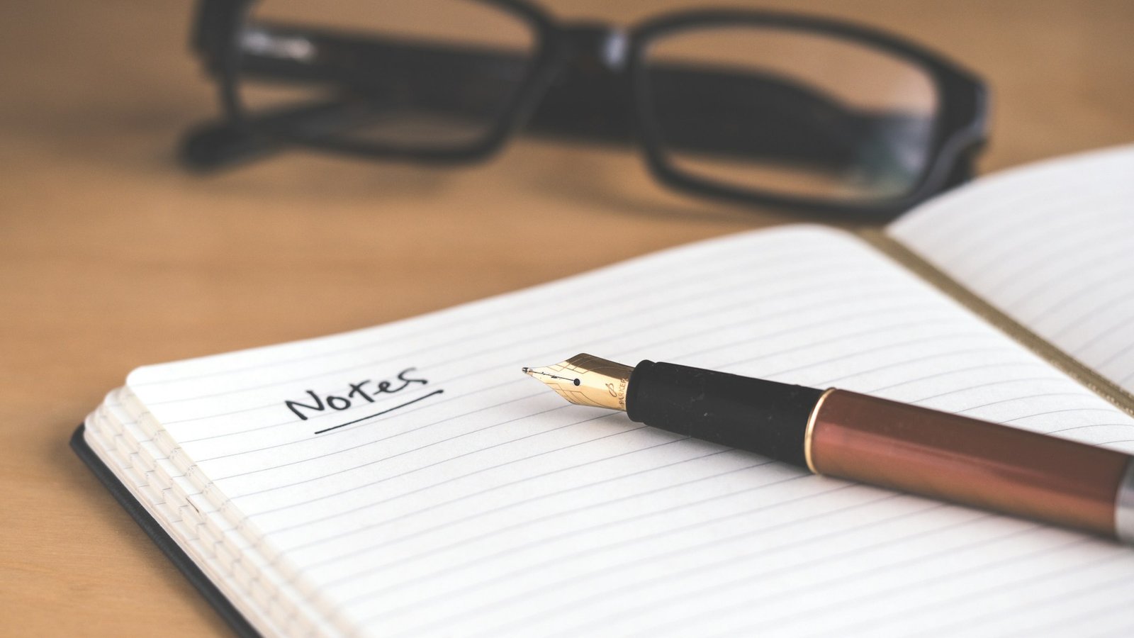 A brown fountain pen resting on an open notebook