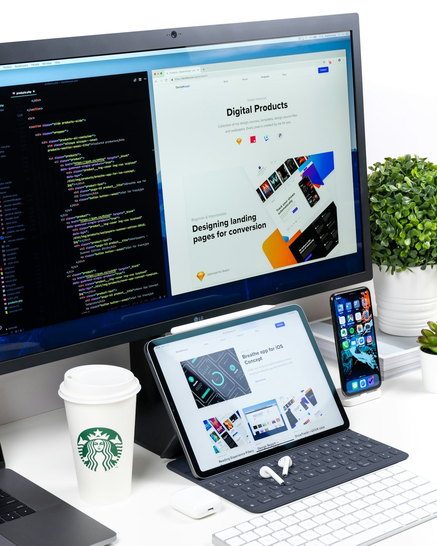 A designer's desk with a monitor, tablet, and phone all showing website and app design work in progress